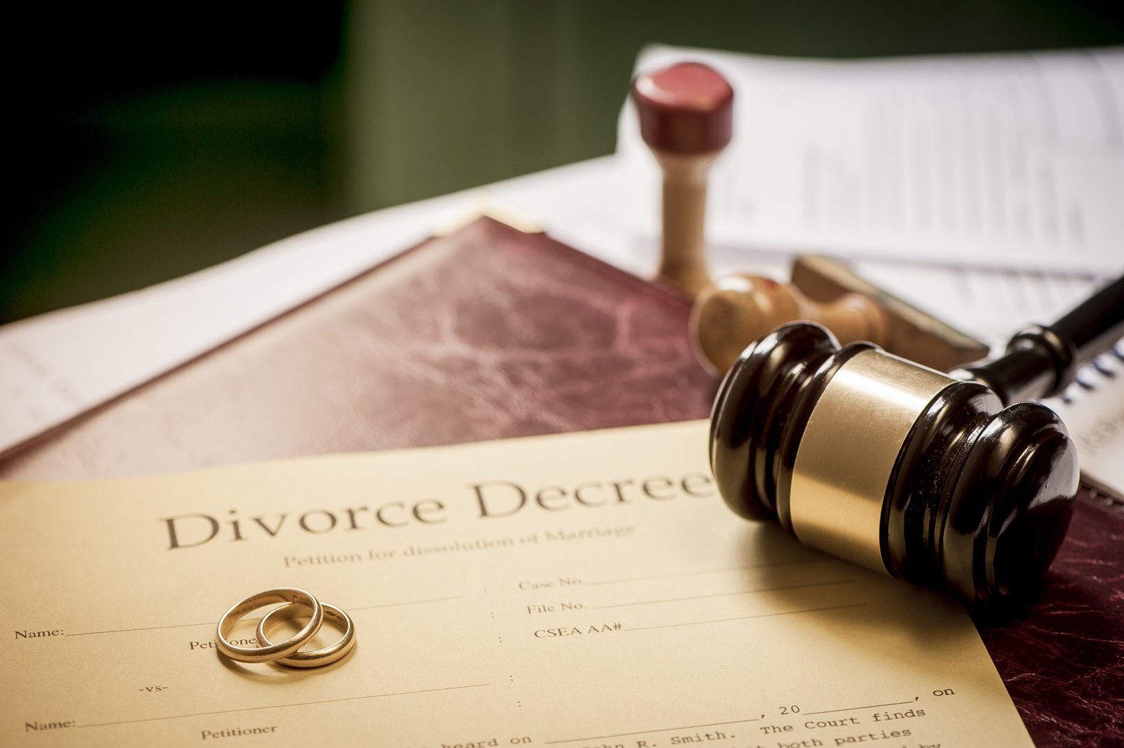 A gavel resting on a divorce decree with two wedding rings on top signifying the end of a marriage and the need for an experienced divorce attorney.