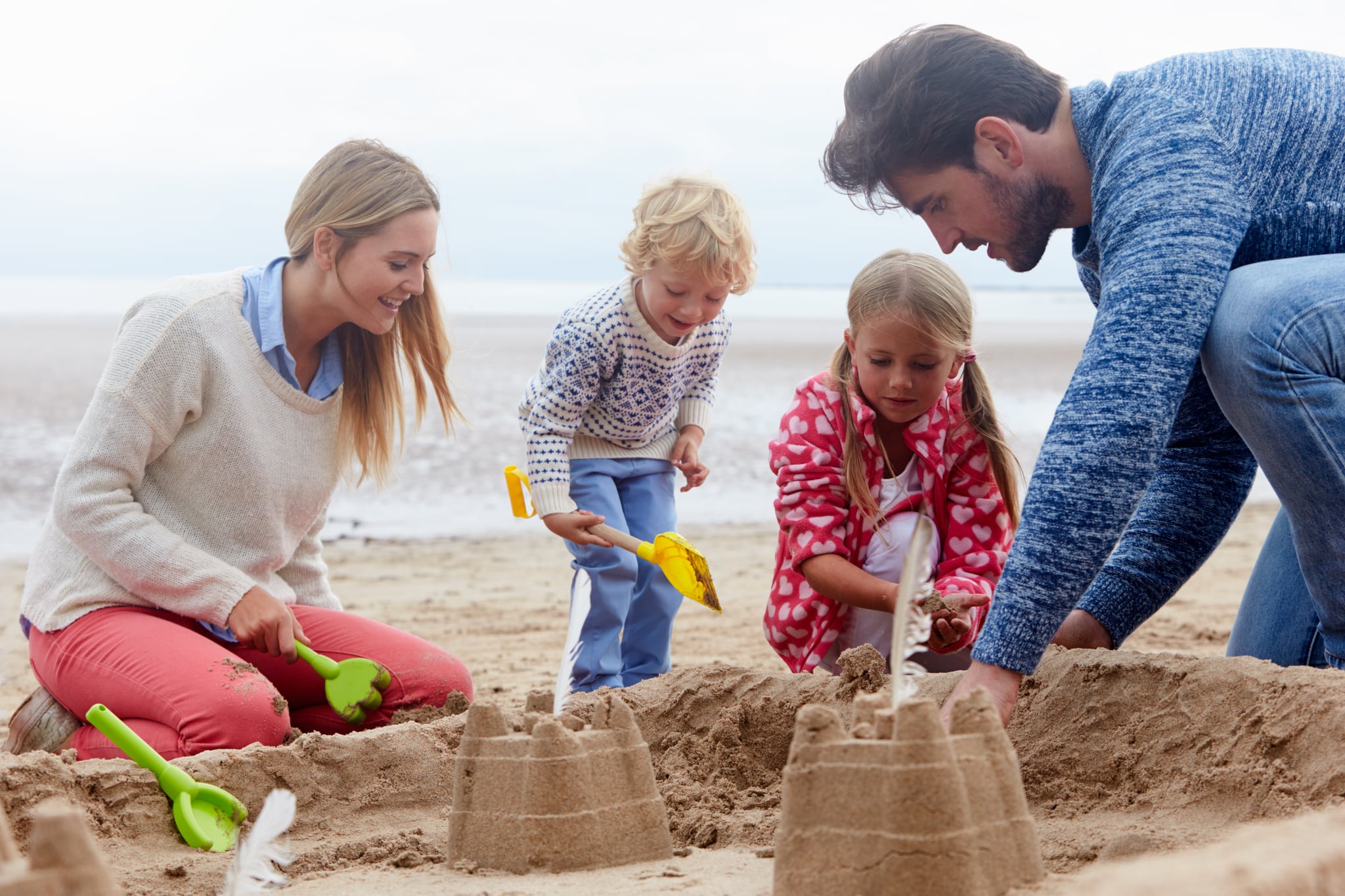 A family of four is building a sandcastle on the beach in Myrtle Beach.