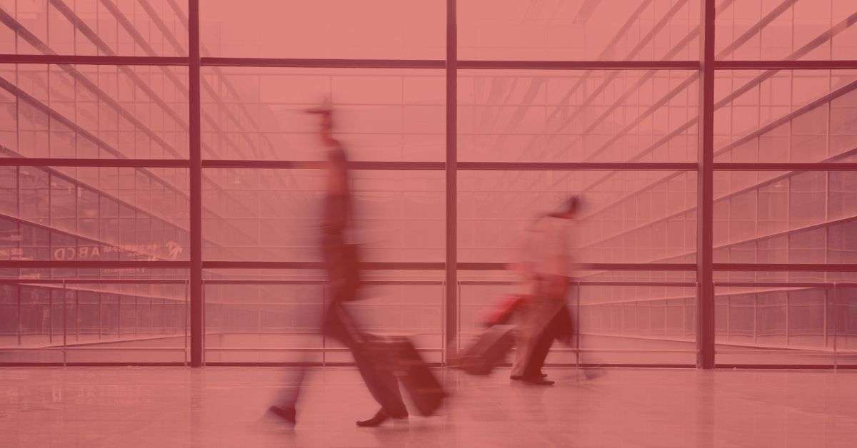 Business travelers walking in an airport with their luggage, representing the search query 'Business travelers using ecofriendly transportation'.