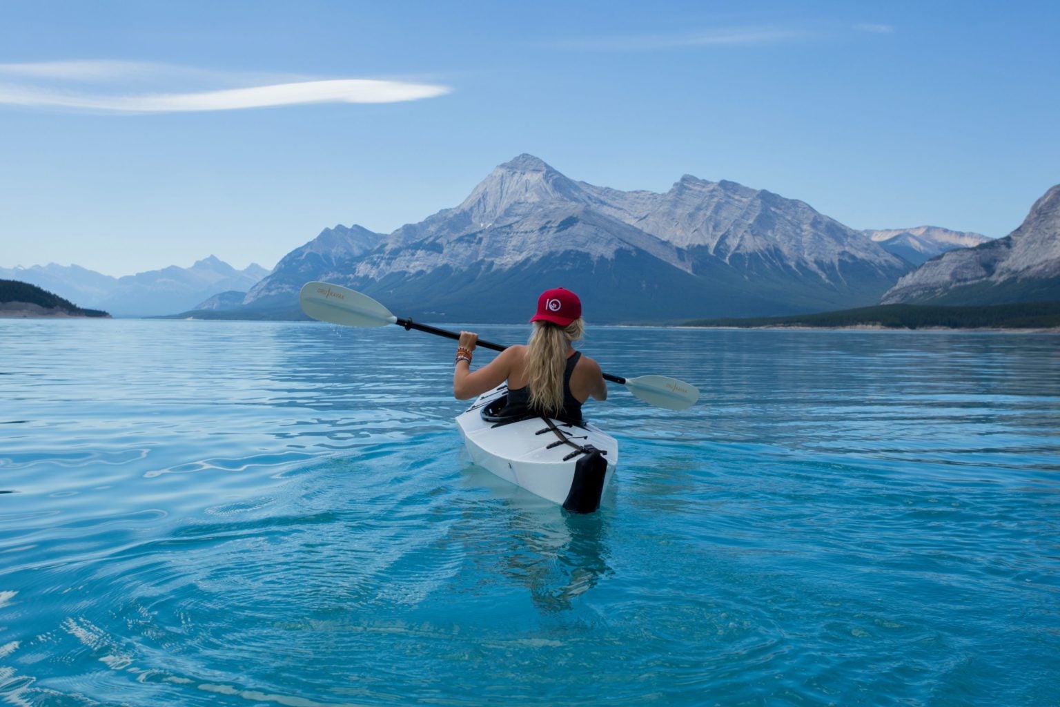 A person kayaking in a lake with mountains in the distance with text overlay 'Adventure Travel Tours 2024'.