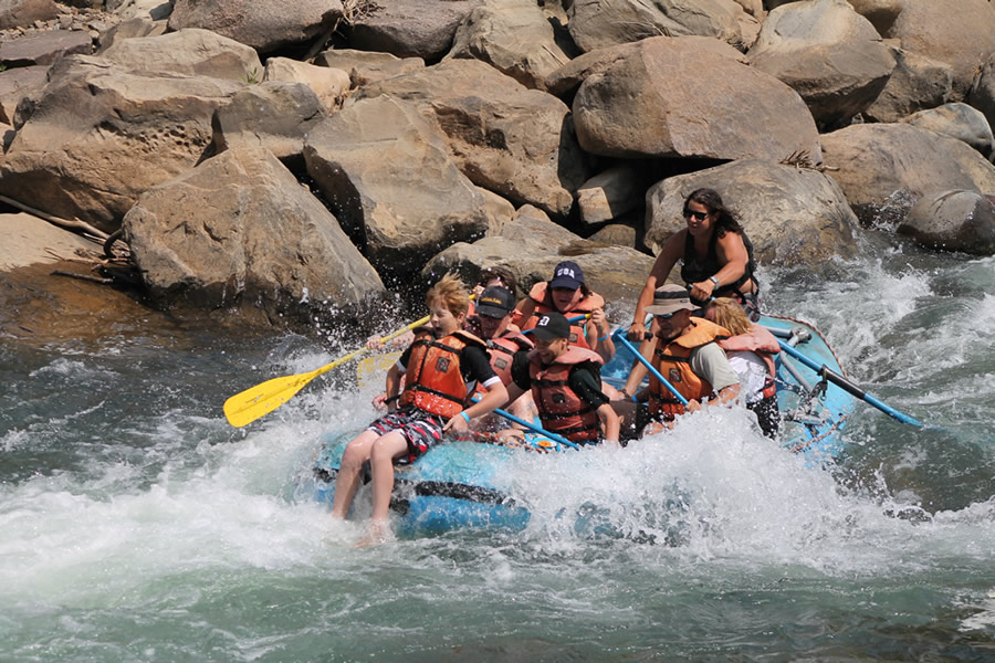 An image of a group of people on a whitewater rafting trip, with rocks in the background.